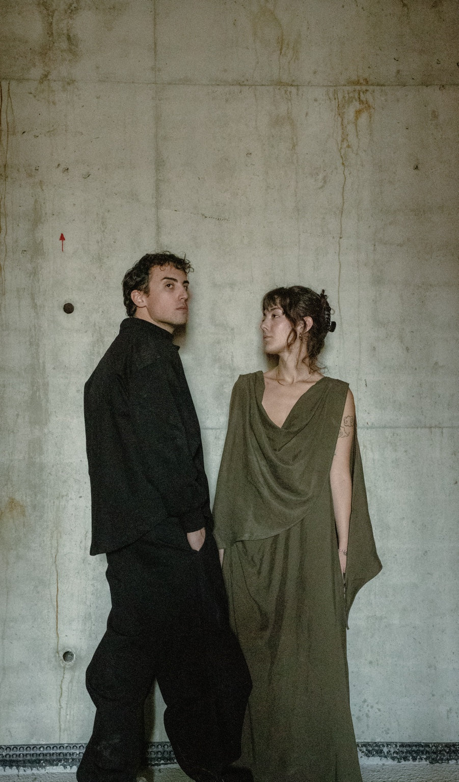 Two models wearing TABBIATH against a concrete wall.