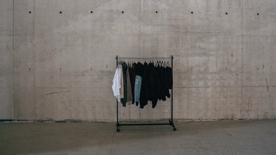 TABBIATH collection on a clothing rail against a concrete wall.